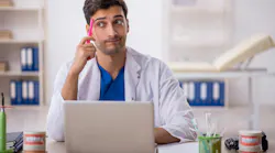 Dentist sitting behind laptop at desk Dentist sitting behind laptop at desk