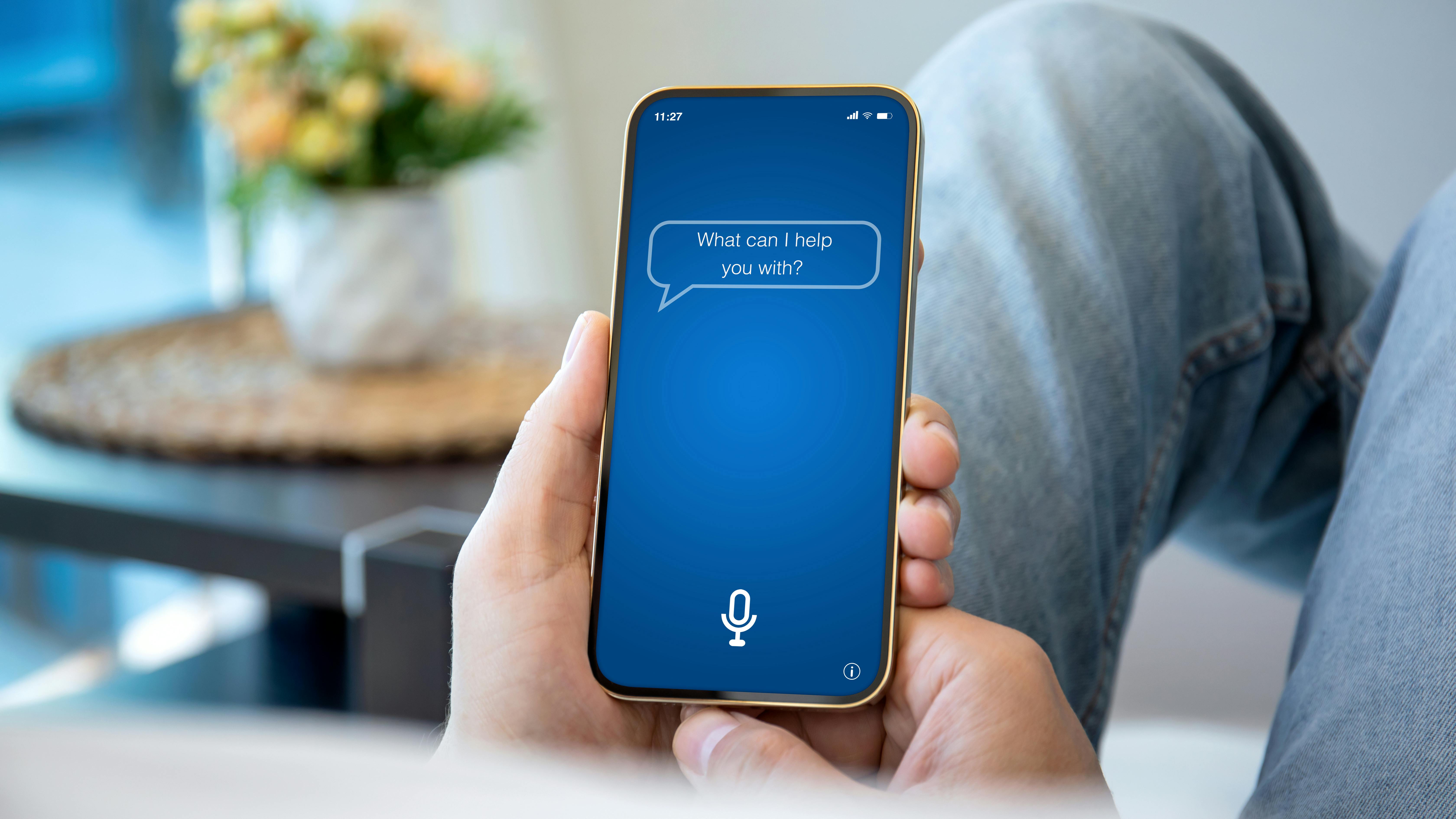 Person holding iPhone with 'What can I help you with' text on screen