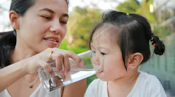 Mother giving child water Mother giving child water