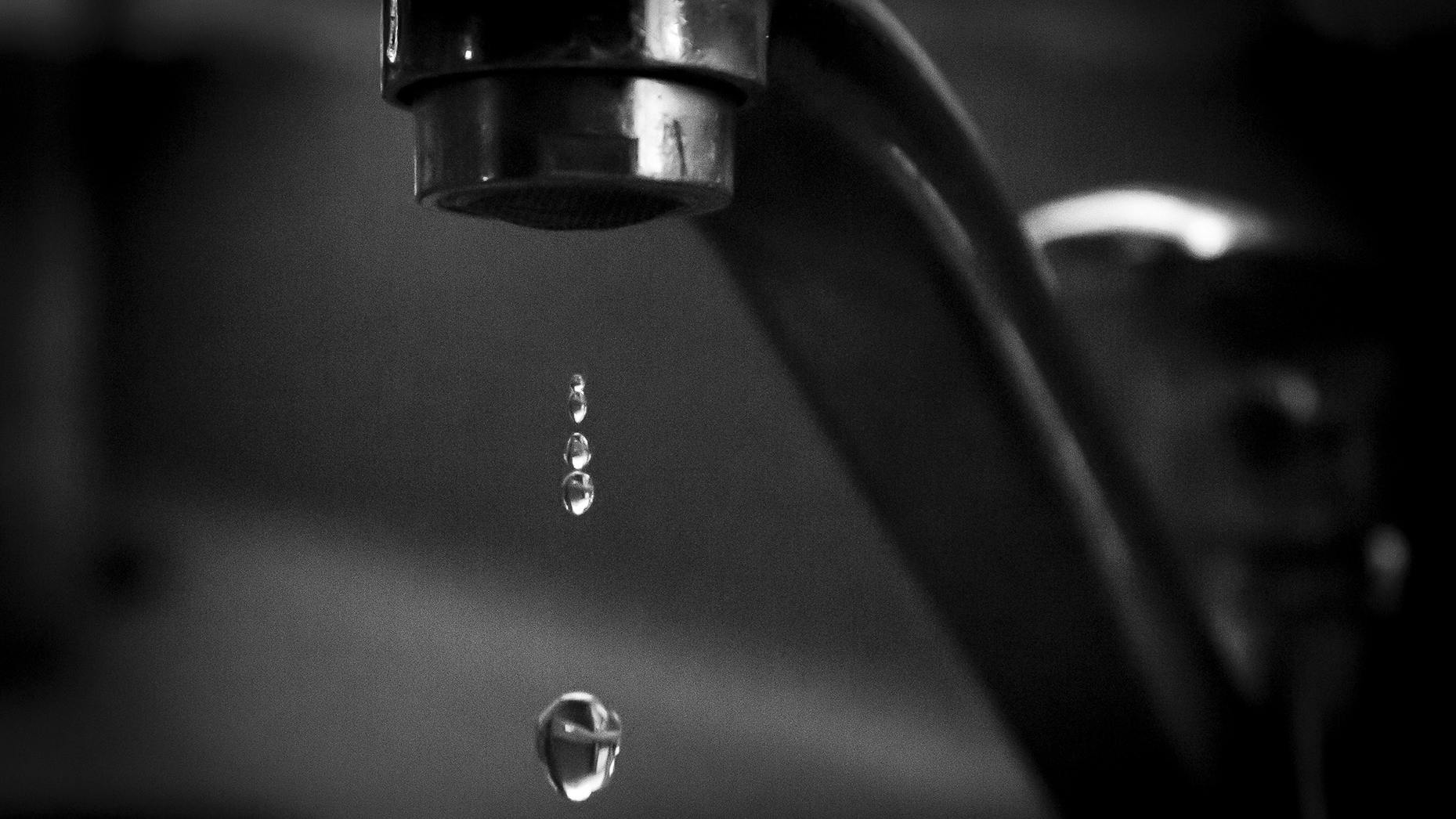 Water drips from a faucet, highlighting the impact of fluoride removal on public health