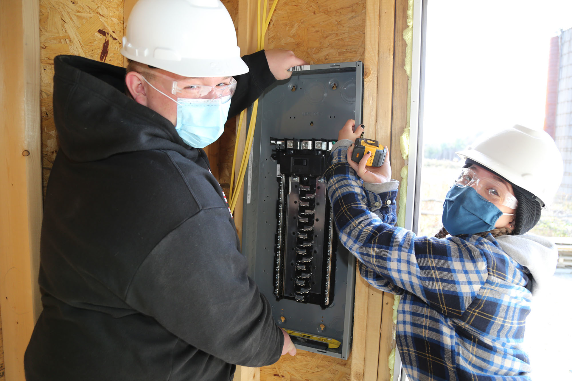 Ulster BOCES Electrical Construction & Maintenance students from Saugerties Central School District, Jonathan Toth (left) and Kaitlyn Lennon, work together to hang an electrical panel at the Habitat for Humanity house in Glasco, N.Y.