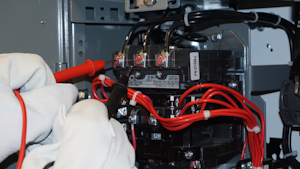 Photo 1. It is possible to drag an electrical arc from Phase B to Phase C (center to right terminals) when measuring voltage. Notice that the worker is pulling the black test lead toward him or herself before placing it on Phase C. Simply sliding the black test lead from the center to the right-hand terminal could establish a phase-to-phase arcing fault through the airspace between the terminals.