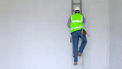 Workman climbing a ladder. Workman in reflective vest and hard hat climbing a ladder, slight motion blur on the man. Workman climbing a ladder. Workman in reflective vest and hard hat climbing a ladder, slight motion blur on the man.