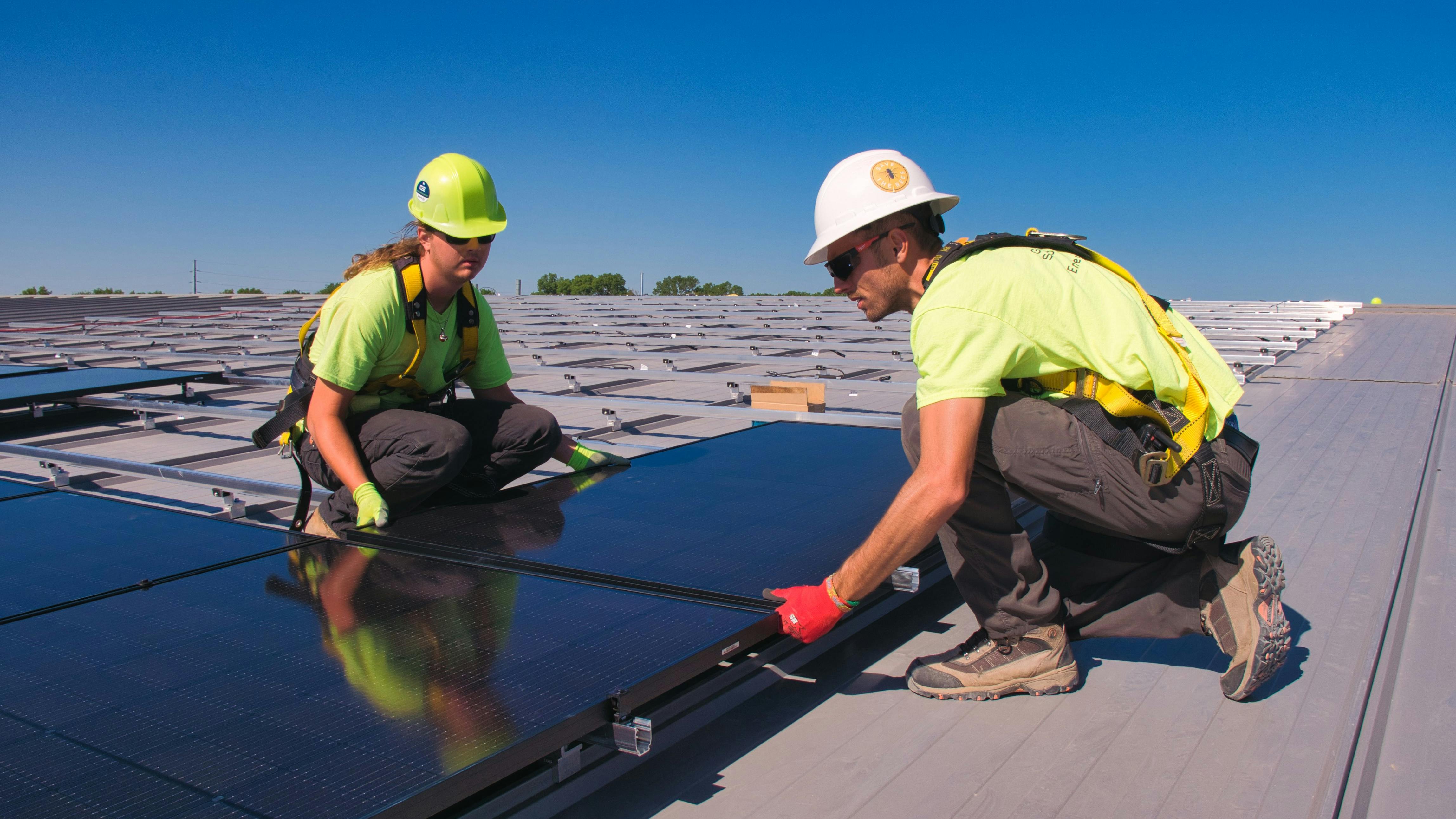 2 workers installing solar panels.