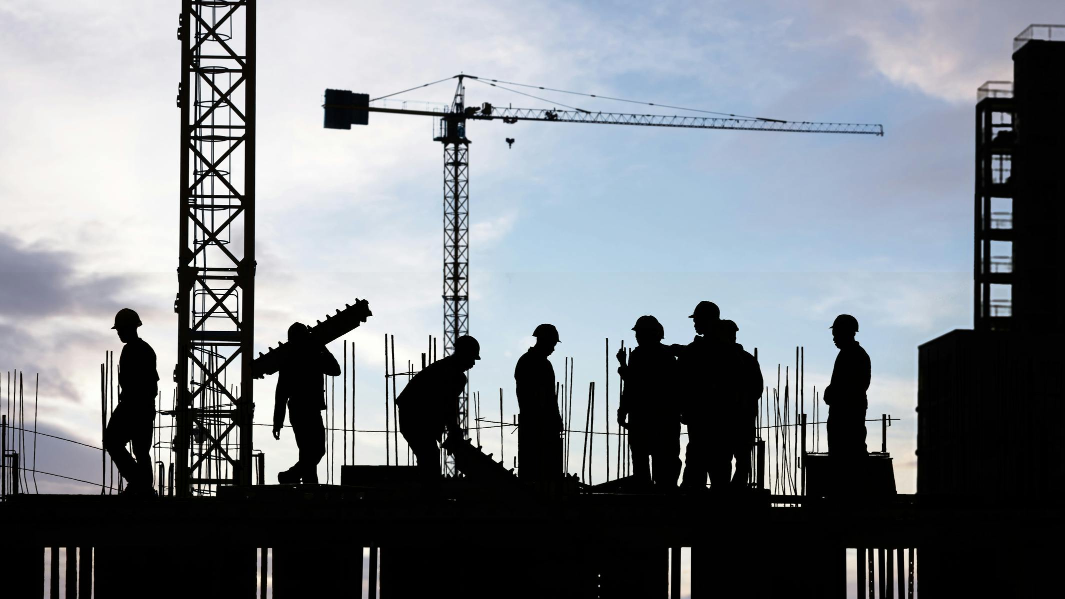 silhouette of construction workers working on scaffolding