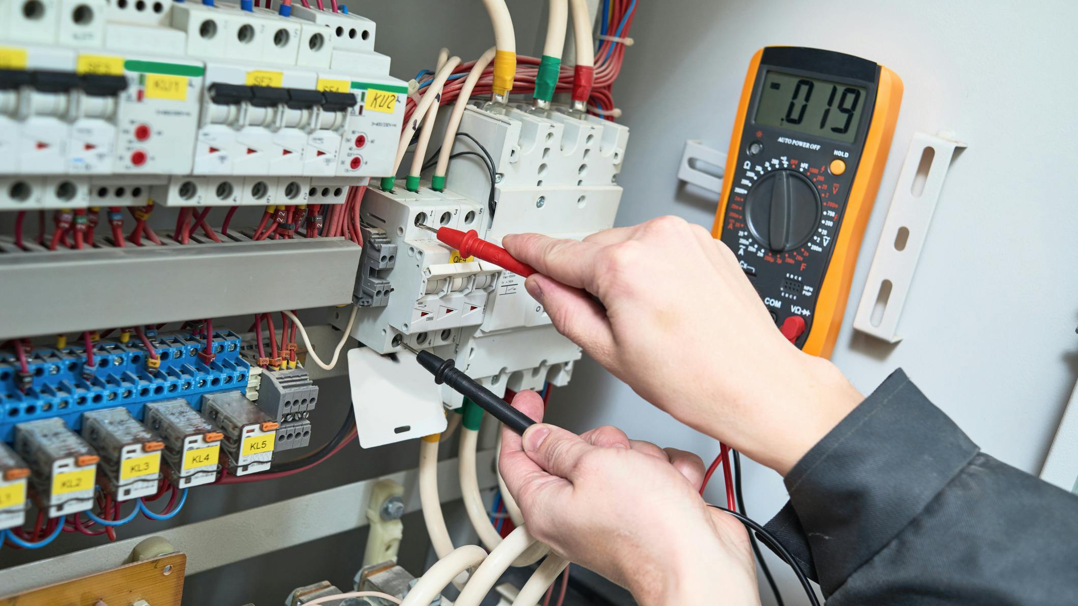 Electrician measurements with multimeter tester. Electrician works. male technician examining fusebox with digital multimeter ac dc tester