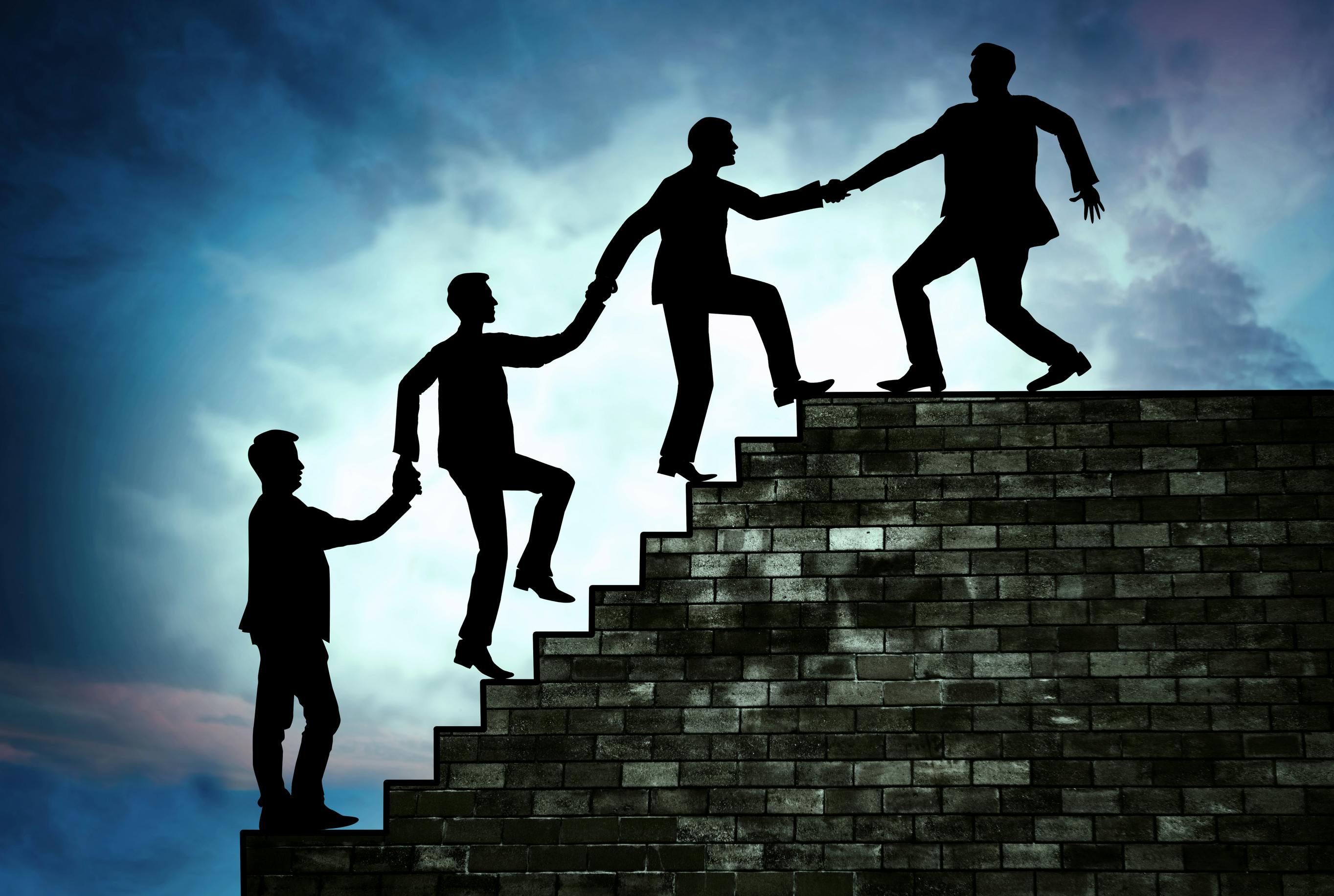 Concept of leadership, with a silhouette of a man pulling his team up to the top of the stairs