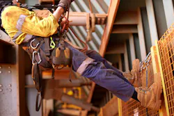Wide angle picture of male worker wearing full safety harness while working at height Wide angle picture of male worker wearing full safety harness while working at height