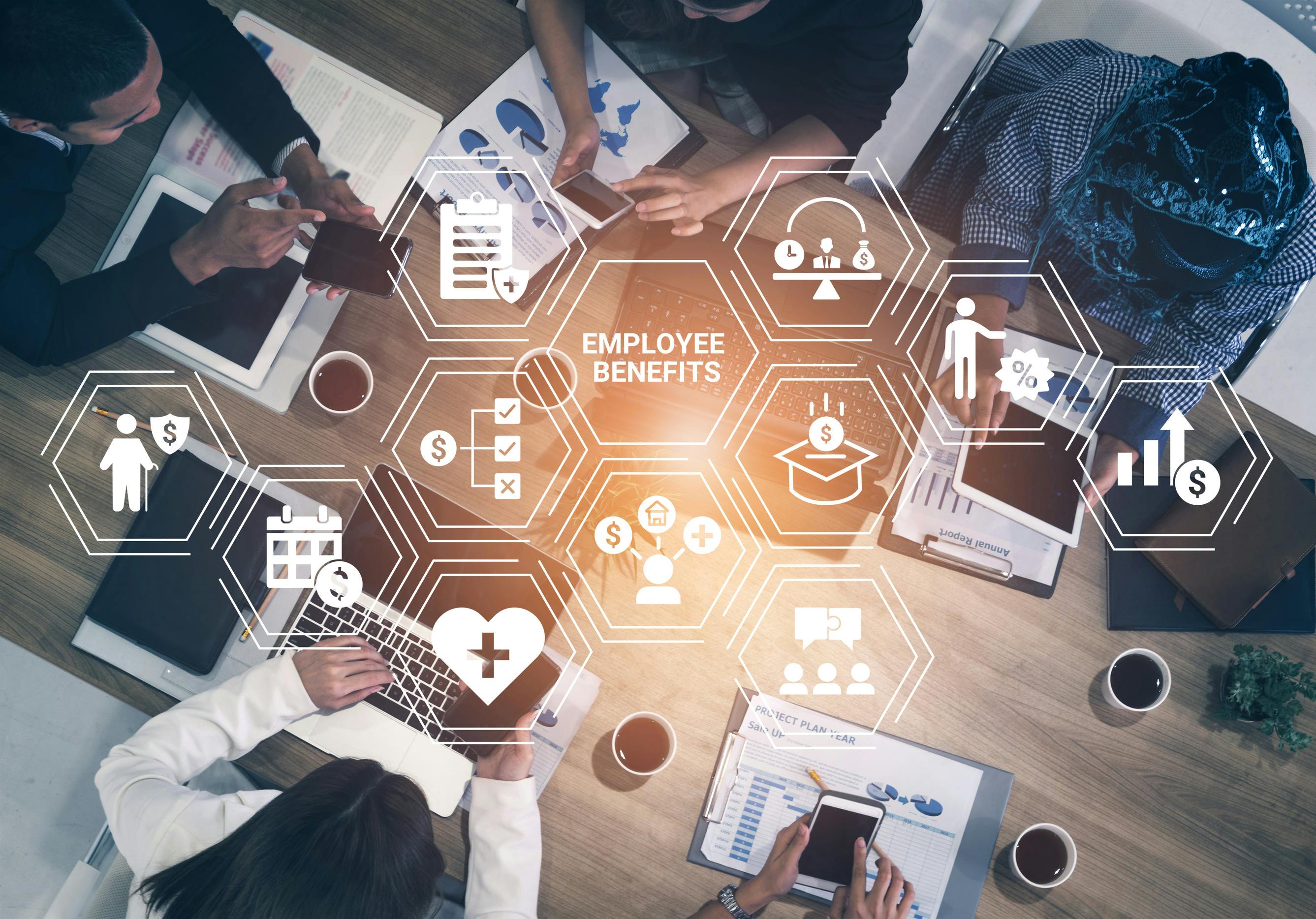 photo of employees working at a table with 'Employee Benefits' and icons of said benefits in white overtop the photo