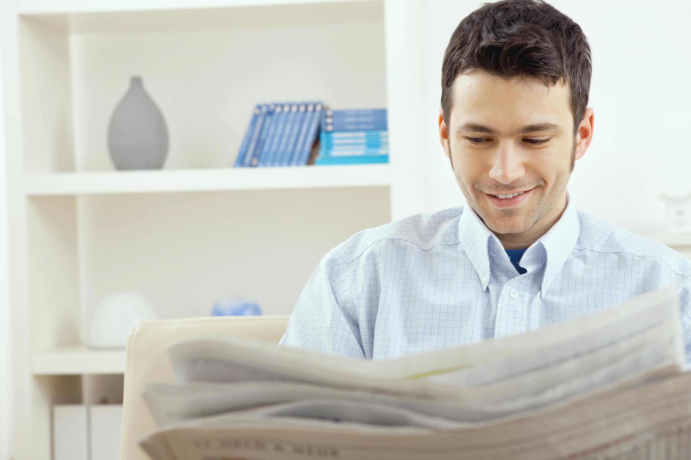 man sitting on couch reading newspaper