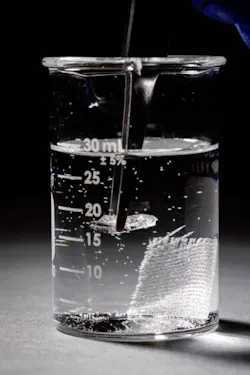 3. Tweezers are used to remove a piece of vitrimer from the solvent. The sheet of reinforcing glass fibers sits in the background. 3. Tweezers are used to remove a piece of vitrimer from the solvent. The sheet of reinforcing glass fibers sits in the background.