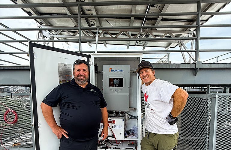 Brooklyn SolarWorks president Gaelen McKee and Brooke Plantz, business development manager for Briggs & Stratton, pose beside the New York city residential battery project adjacent to the rooftop solar array. Image credit Brooklyn SolarWorks.