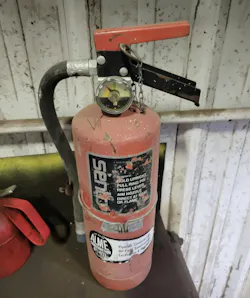 This fire extinguisher is out of service, as evidenced by the arrow not in the green. It also needs to be mounted, not loose on a table. It is also missing a fire extinguisher sign above it and needs to be tagged by the servicing company to indicate when it was last serviced. This fire extinguisher is out of service, as evidenced by the arrow not in the green. It also needs to be mounted, not loose on a table. It is also missing a fire extinguisher sign above it and needs to be tagged by the servicing company to indicate when it was last serviced.