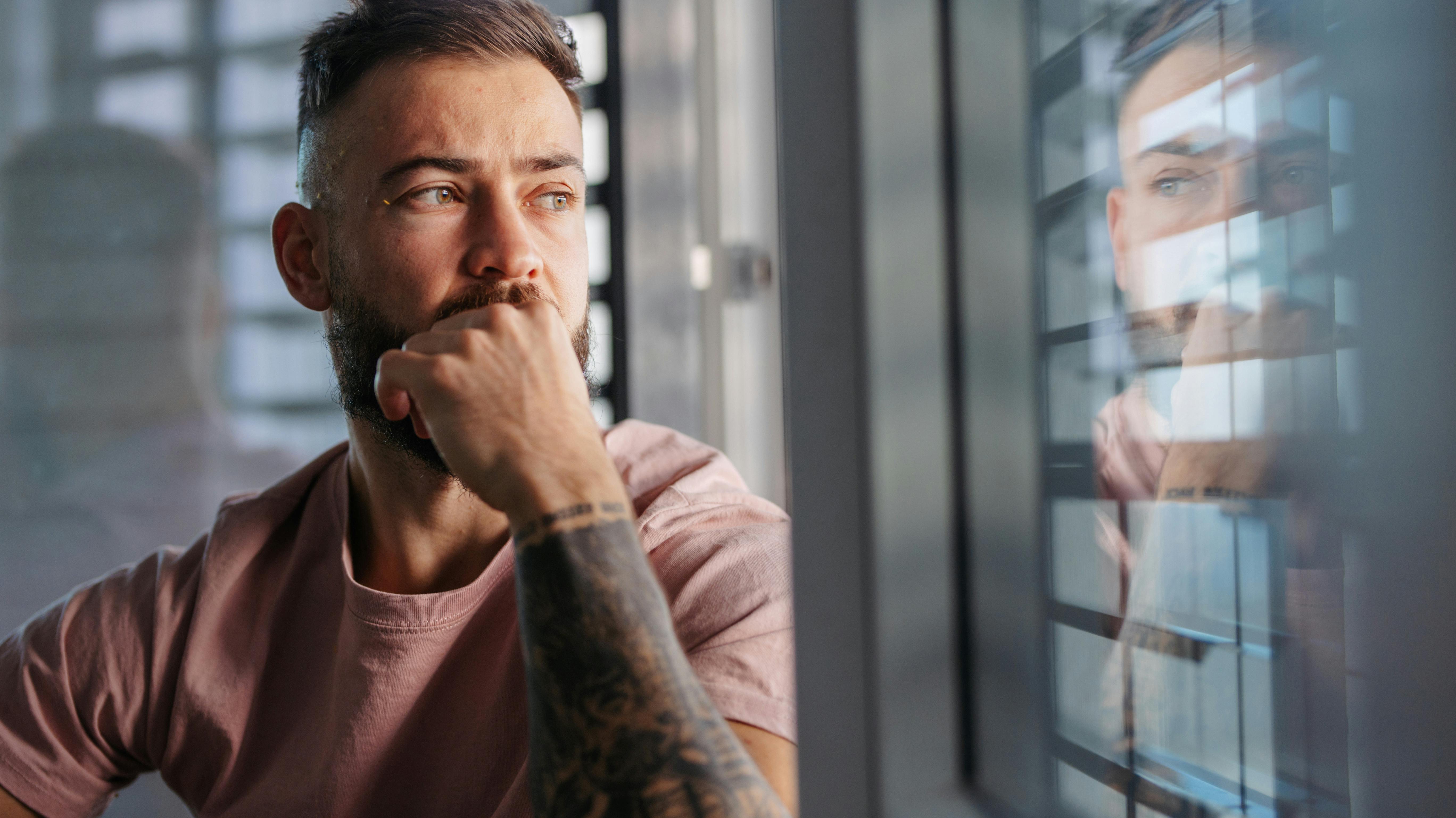 Man with tattooed arm reflecting
