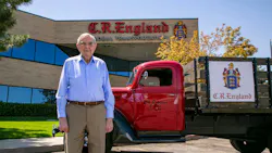 G.E. “Gene” England stands with a vintage C.R. England truck outside the fleet's Salt Lake City headquarters in 2023. G.E. “Gene” England stands with a vintage C.R. England truck outside the fleet's Salt Lake City headquarters in 2023.
