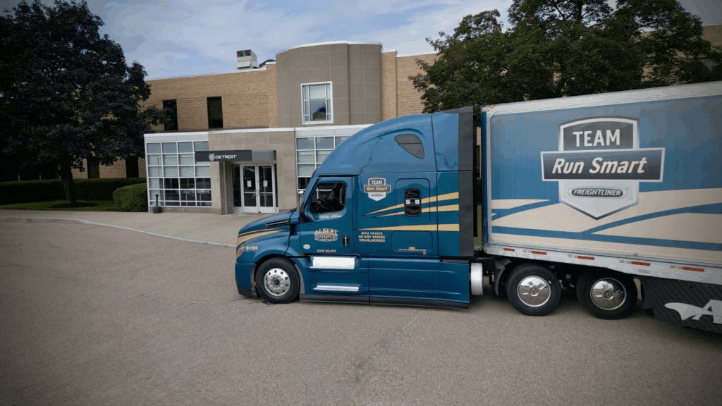 Albert Transport Freightliner Team Run Smart truck parked outside Detroit Diesel building, showcasing fuel-efficient fleet operations.