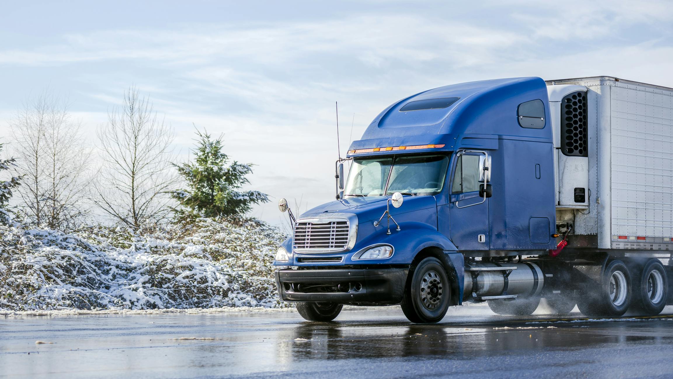 blue tractor with refrigerated trailer in winter