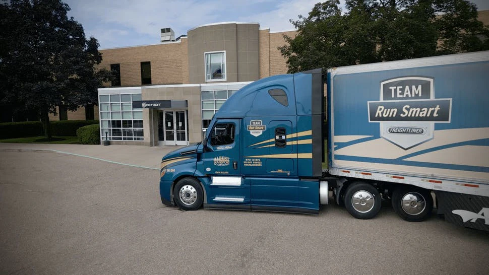 A blue and yellow Albert Transport Freightliner Cascadia truck pulling a Team Run Smart trailer.