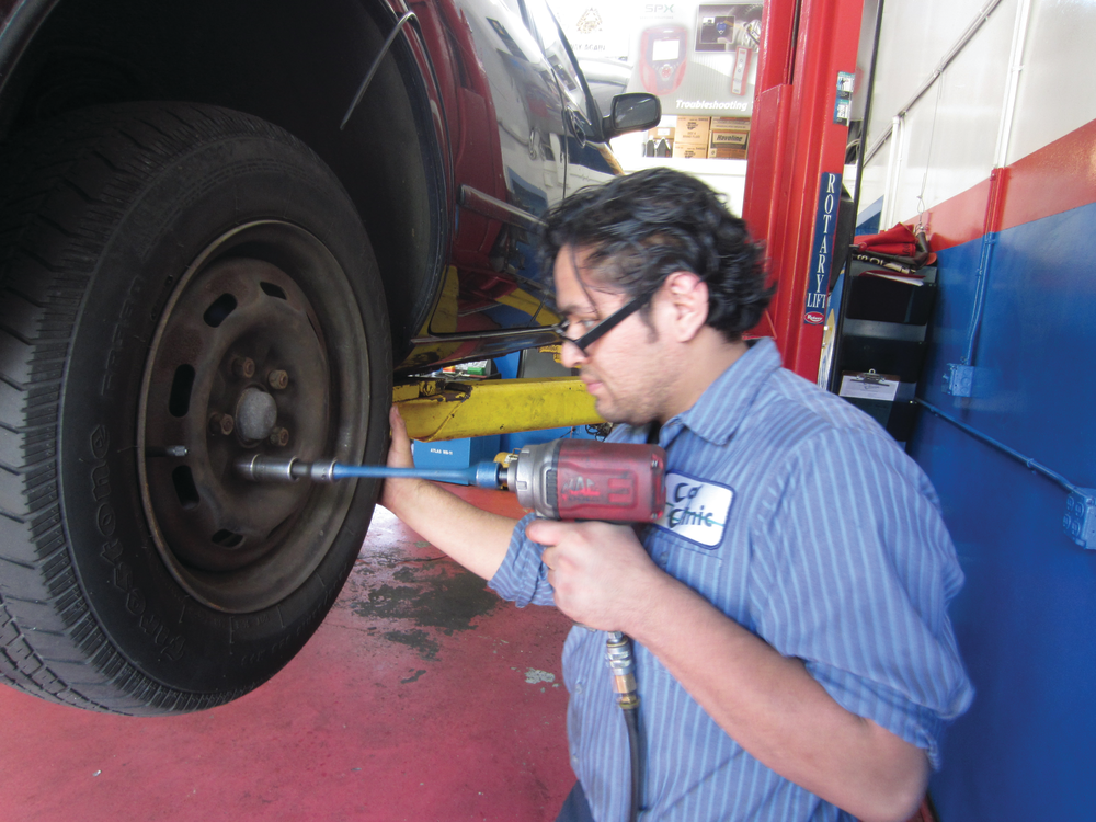 Figure 6: A mechanic using a torque stick to properly tighten lug nuts.