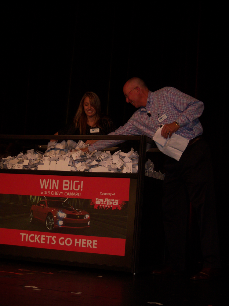 Bruce Weber, president of ISN, draws the name of a cash prize winner during the awards dinner, assisted by Melissa Sanders.