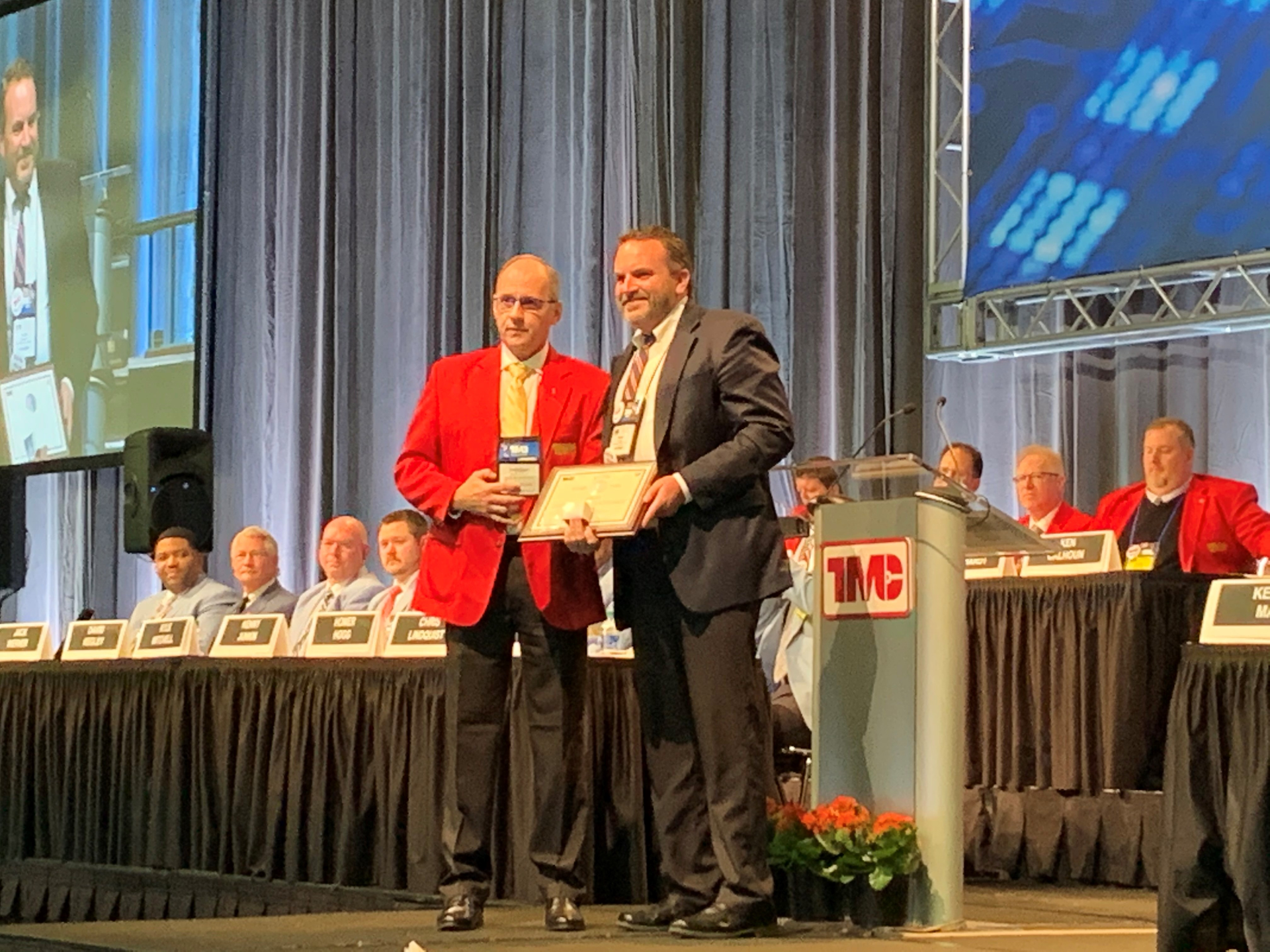 Kenneth Calhoun presents the Silver Spark Plug award to Peter Savage, director of quality and implementations at Clarke Power Services during the TMC Fleet Operator's Forum.