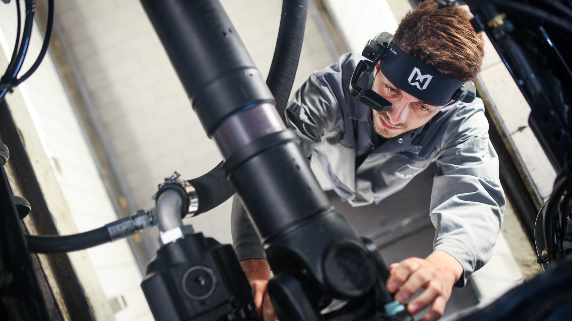 A MHS Truck & Bus technician works on a vehicle with help from his RealWear HMT-1 headset.