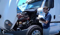Technician looks at diagnostic tablet for truck Technician looks at diagnostic tablet for truck
