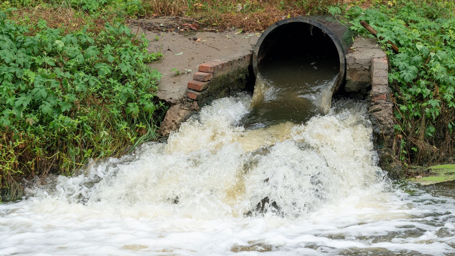 Waste water sewage from a pipe into the river. Water pollution, environment contamination concept