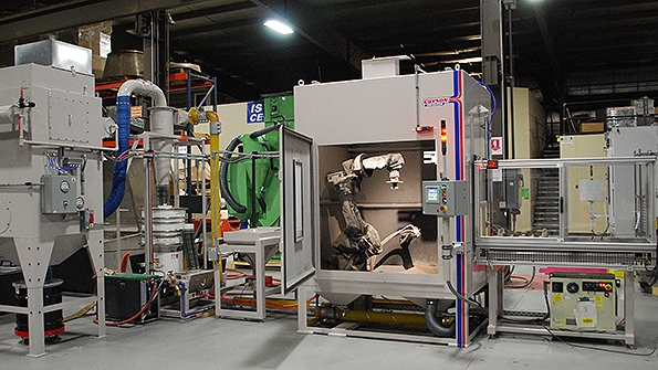 The Guyson RB10TC robotic gritblast system with a precision transfer cart to carry pallets of turbine blades in and out of the blasting chamber where each component is grasped and exposed to the media stream from a single blast gun according to a programmed processing routine