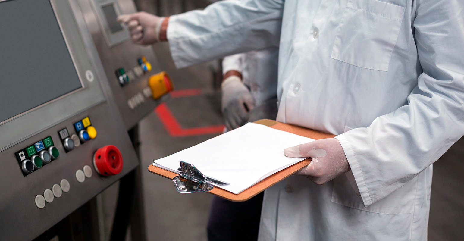 Two factory engineers operating a machine, with a clipboard.