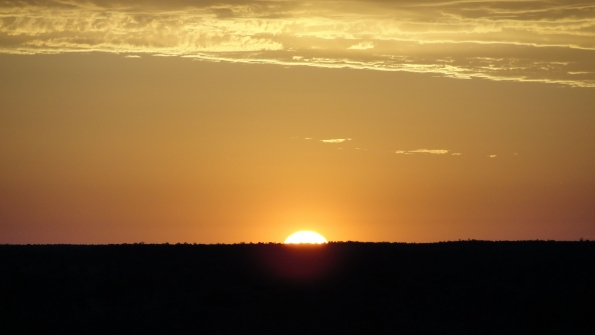 The sun rising over the Australian Desert The cool of the night was about to vanish in a wave of heat as the brightening light washed over the desert and Ayers Rock