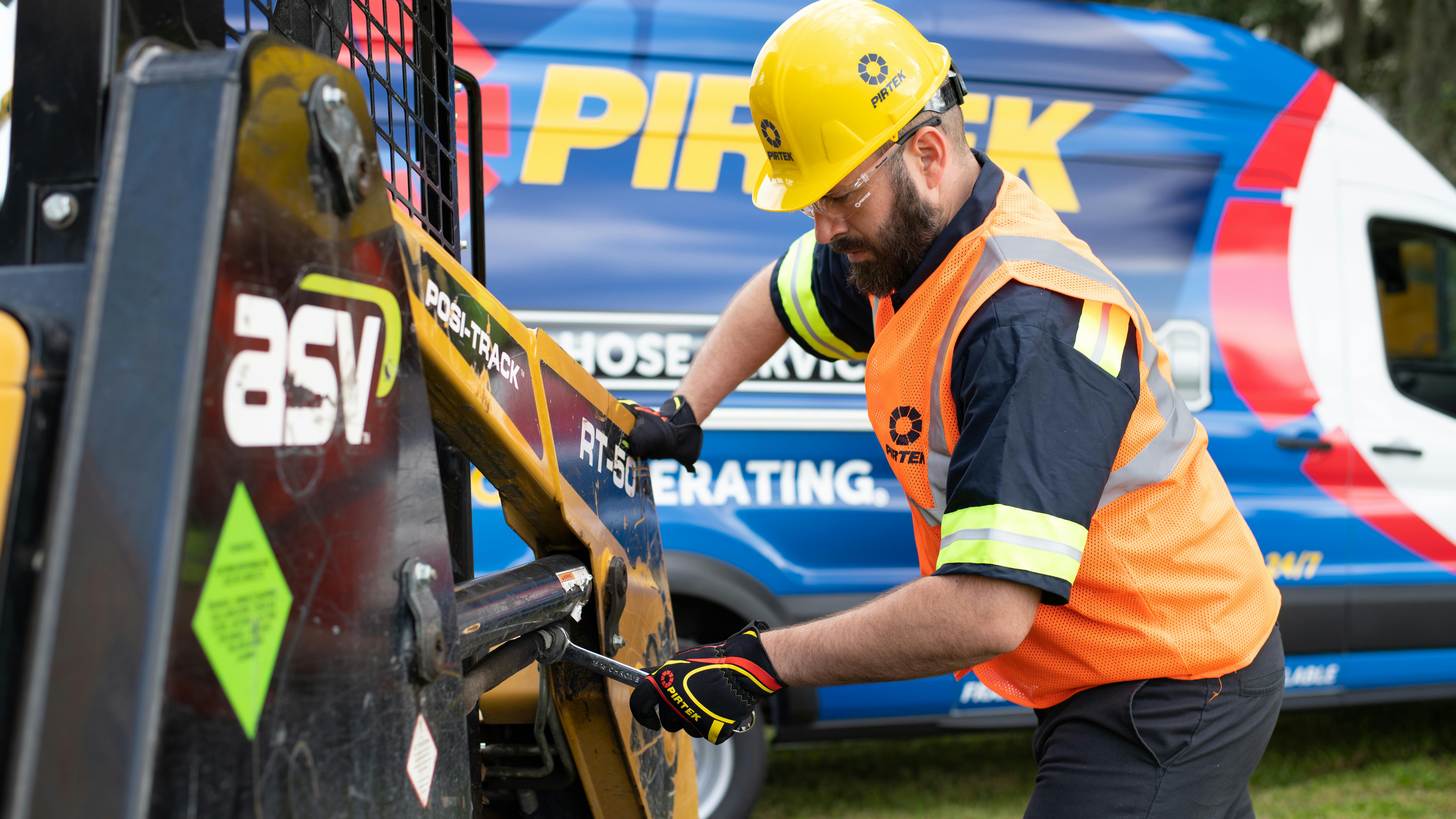A technician performing hydraulic hose services on a piece of construction equipment