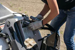 Person attaching hydraulic hoses onto Bobcat machine Person attaching hydraulic hoses onto Bobcat machine