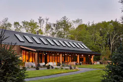 An exterior view of the AutoCamp Catskills location showcases the two adjoining barns nestled within the forest. An exterior view of the AutoCamp Catskills location showcases the two adjoining barns nestled within the forest.