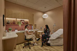 Consult rooms are decorated with terracotta orange walls, rust-colored privacy curtains, decorative lighting, plants, artwork, and warm wood cabinetry. Consult rooms are decorated with terracotta orange walls, rust-colored privacy curtains, decorative lighting, plants, artwork, and warm wood cabinetry.