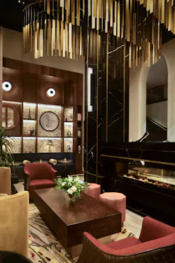 Lounge seating area in hotel lobby with dark wood coffee table and paneling, and gold-metallic ceiling fixture. Lounge seating area in hotel lobby with dark wood coffee table and paneling, and gold-metallic ceiling fixture.