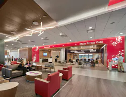 Lounge area and cafe with bright, red wall graphics, wood flooring, and linear lighting. Lounge area and cafe with bright, red wall graphics, wood flooring, and linear lighting.