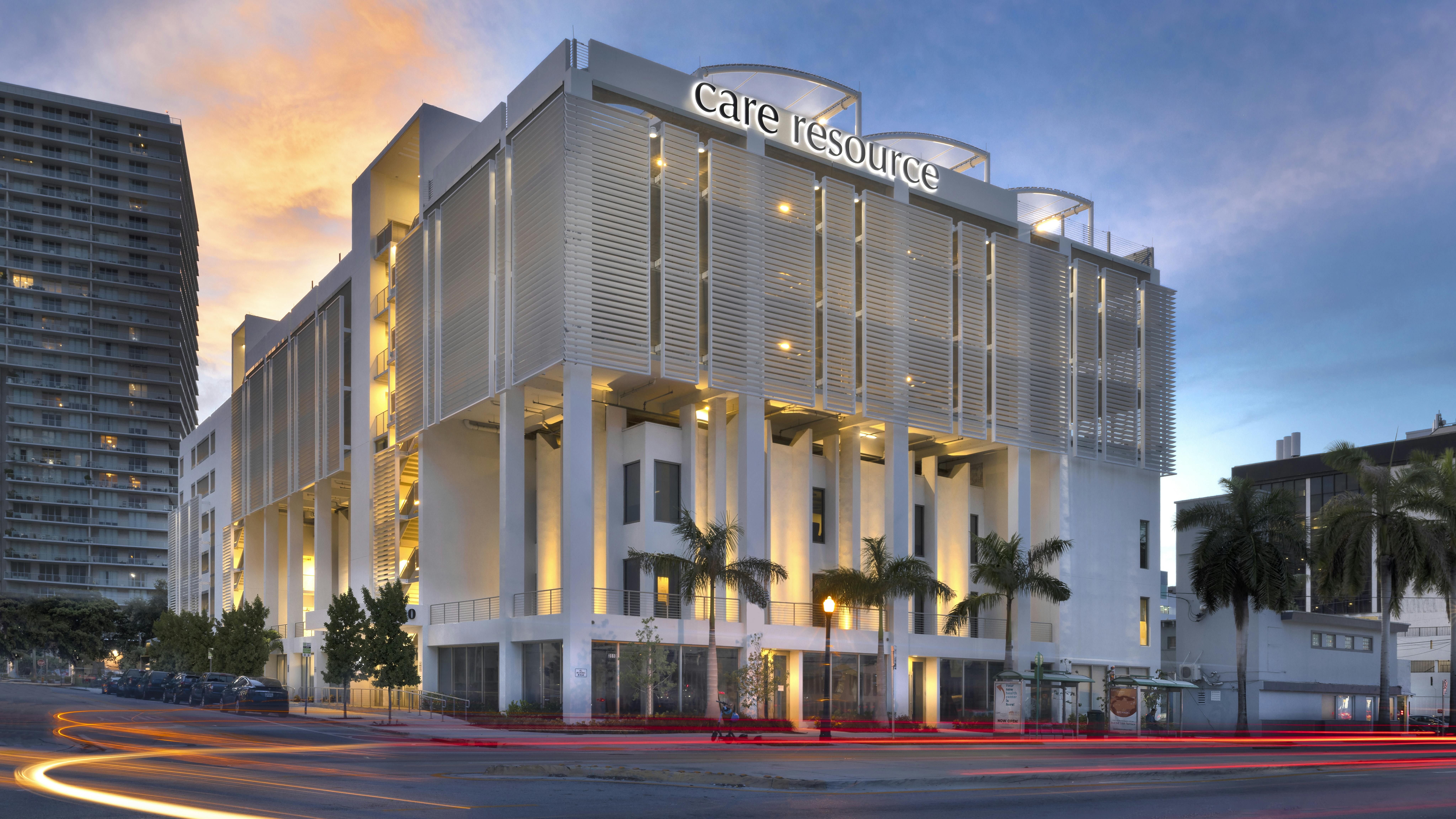 Street level view of exterior facade of Care Resource health center in Miami at dusk.