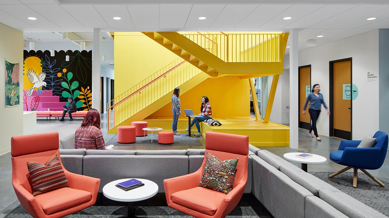 Perkins&Will Interior Design at Family Tree Clinic shows a brightly accented waiting area with grounding neutrals and a vibrant yellow stairwell.
