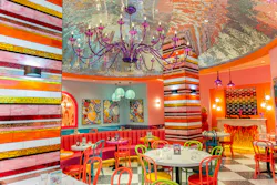 Brightly colored dining area with multi-colored glass tiles, chandeliers, and chairs. Brightly colored dining area with multi-colored glass tiles, chandeliers, and chairs.