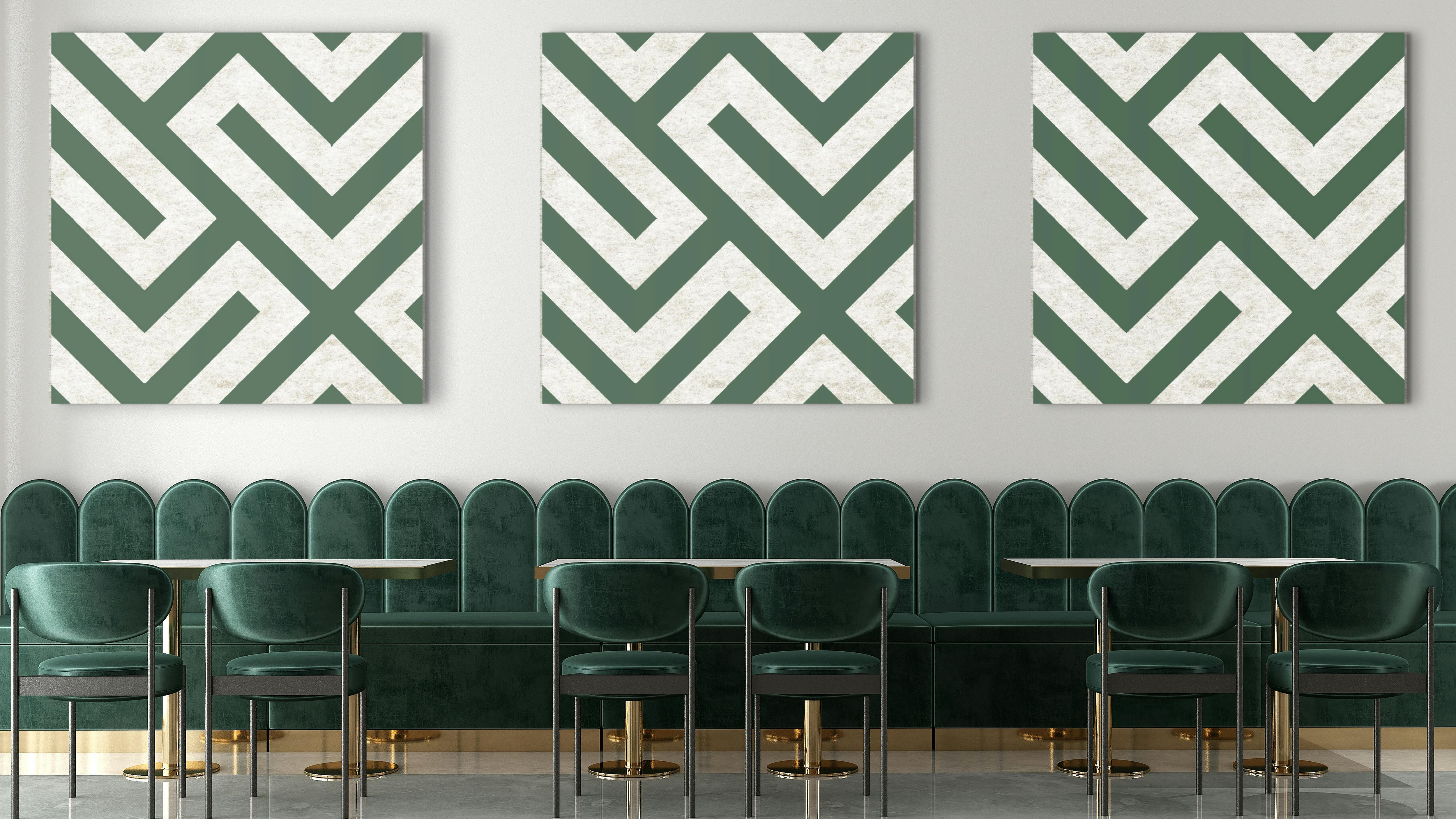 Three green and white art pieces hang above a bench.