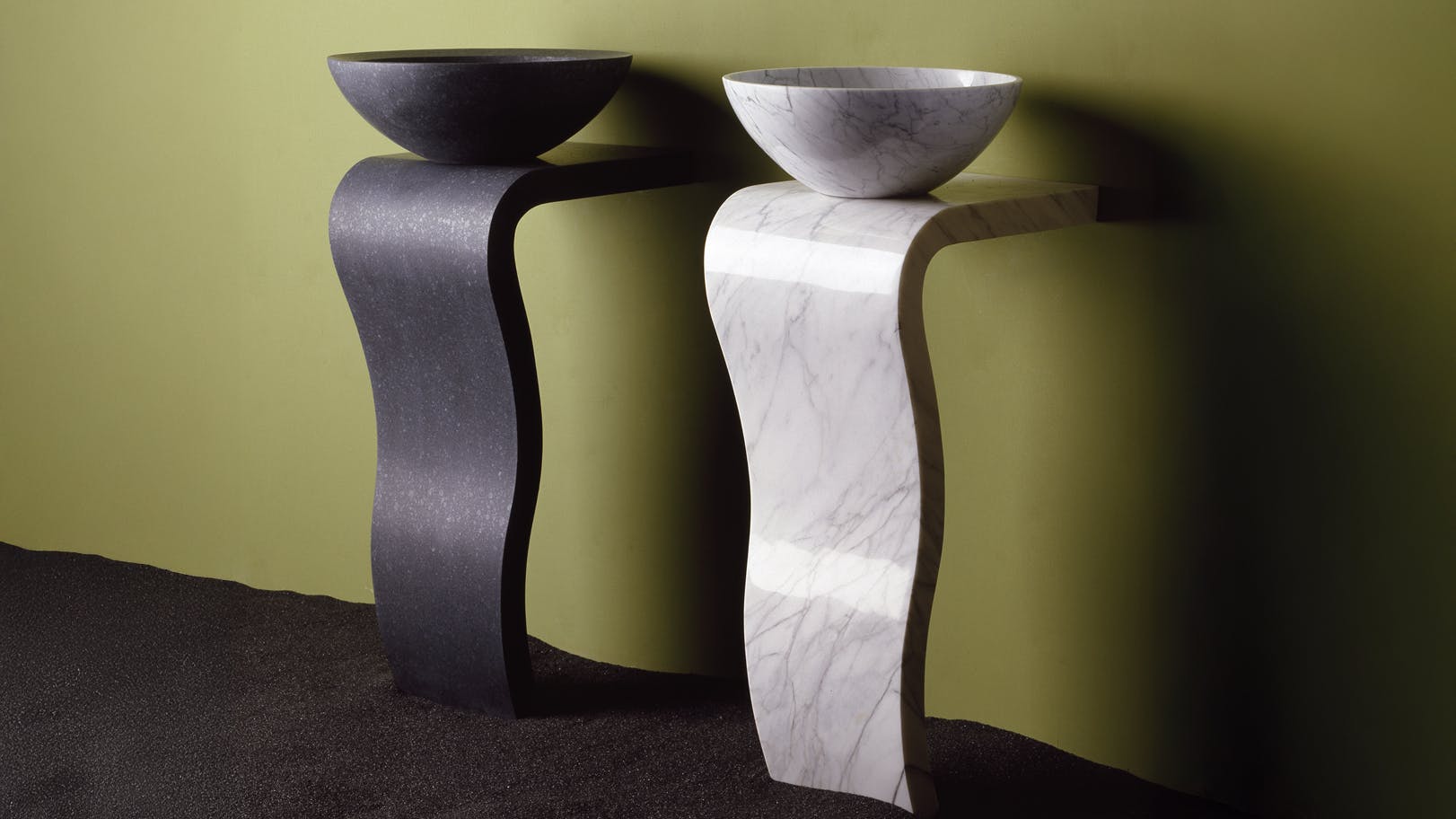 Stone Forest's Wave Pedestals are hand-carved sink bases, shown in Carrara Marble and Honed Basalt.