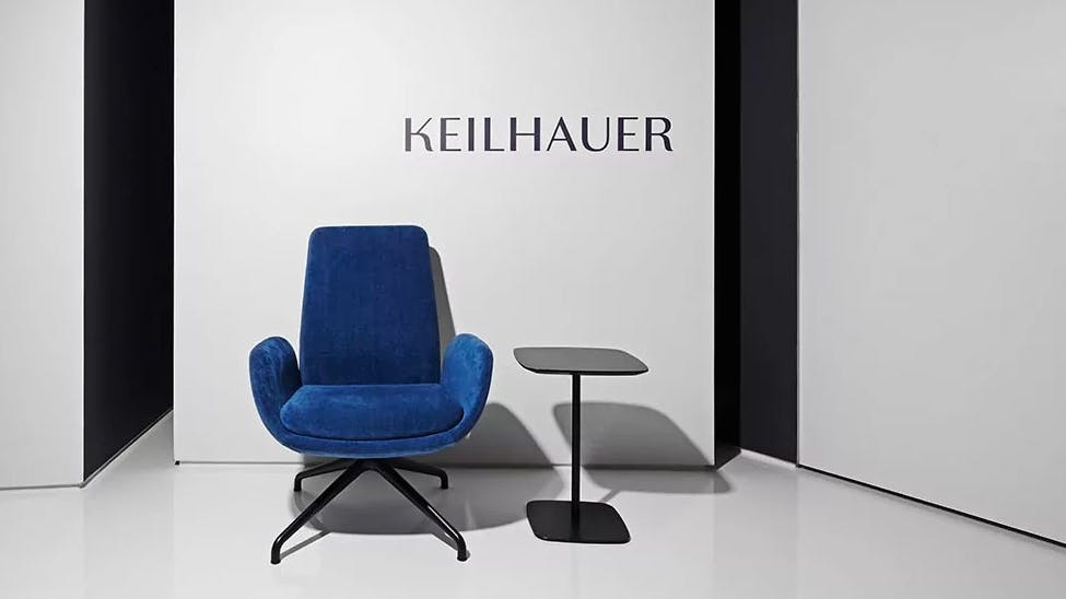 Keilhauer's Forsi chair is part of a conference collection built to meet the needs of the modern meeting. It is situated in front of the Keilhauer name and beside a side table.
