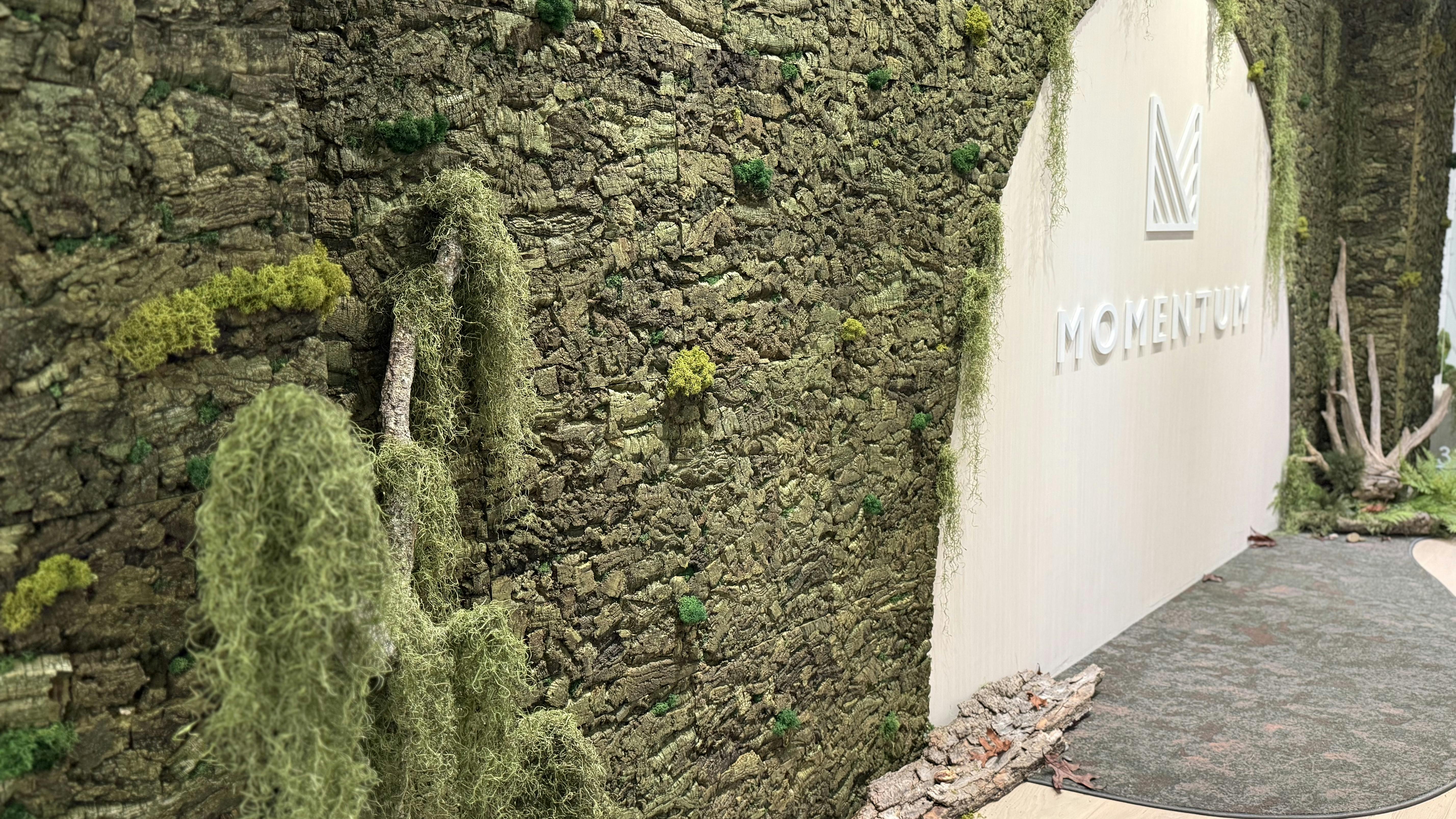 The Momentum showroom at NeoCon 2025 features an expansive green wall.