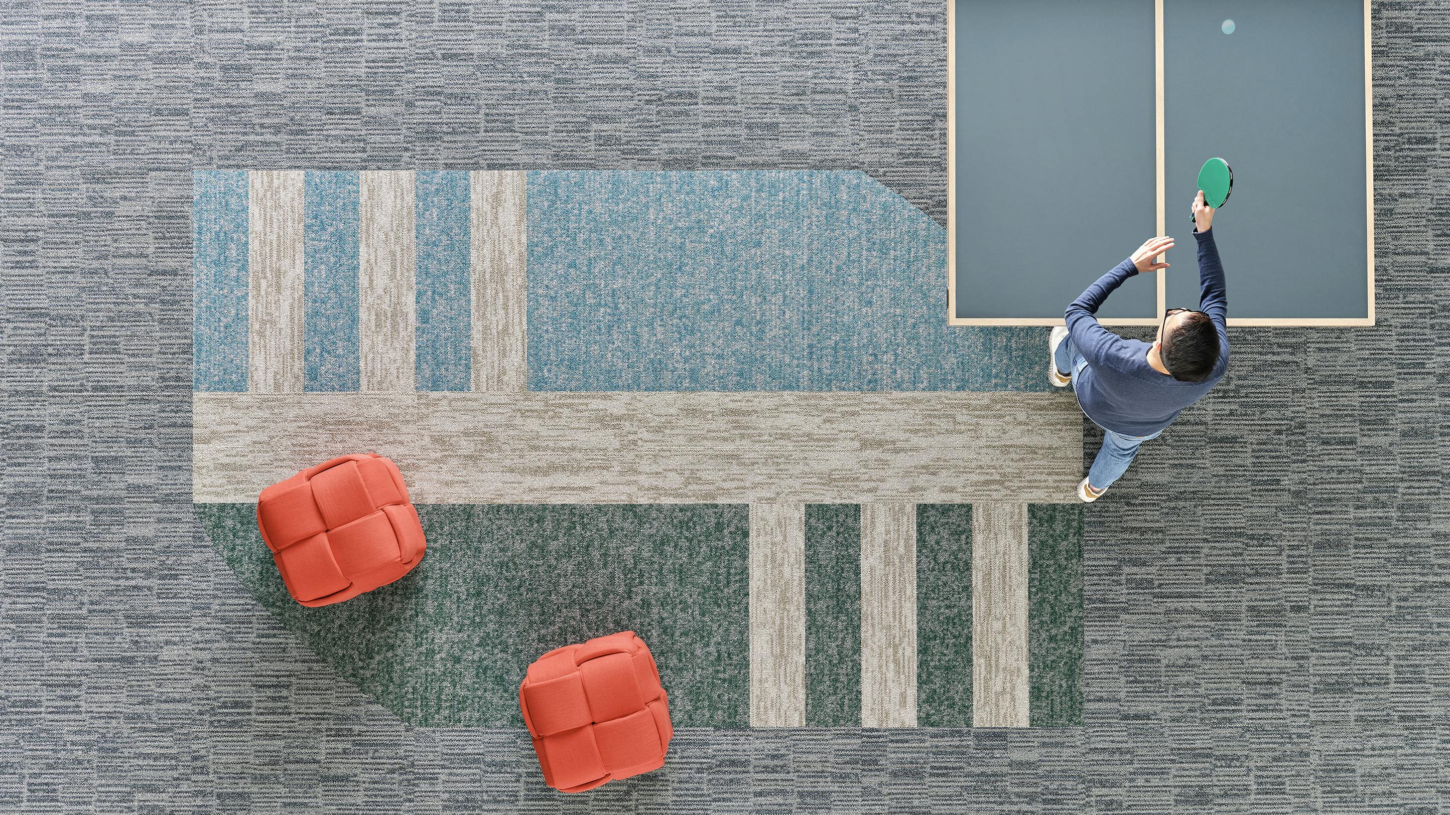 Overhead view of carpet installed on floor looking down on ping pong player at table.