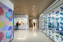 Corridor in children's unit with vibrant colored clouds on one wall and blue butterflies printed on glass divider Corridor in children's unit with vibrant colored clouds on one wall and blue butterflies printed on glass divider