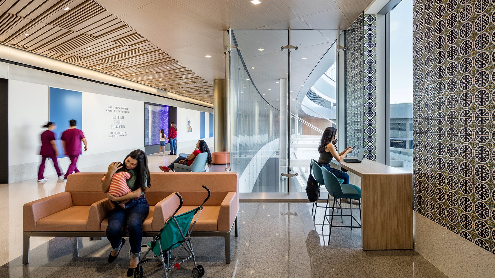 University Health Women's & Children&rsquo;s Hospital waiting area with earth-tone furniture, patterned wall covering, and wood-look ceiling