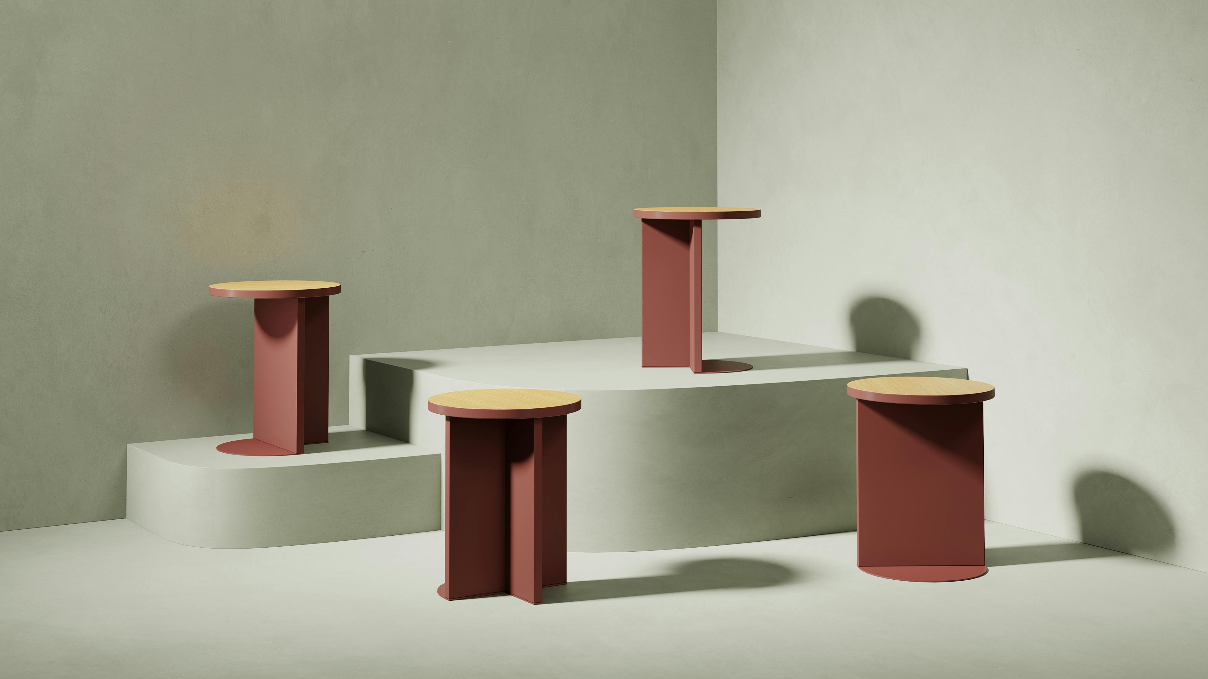 Four small, circular side tables with wood tops on display on pedestals of differing heights.