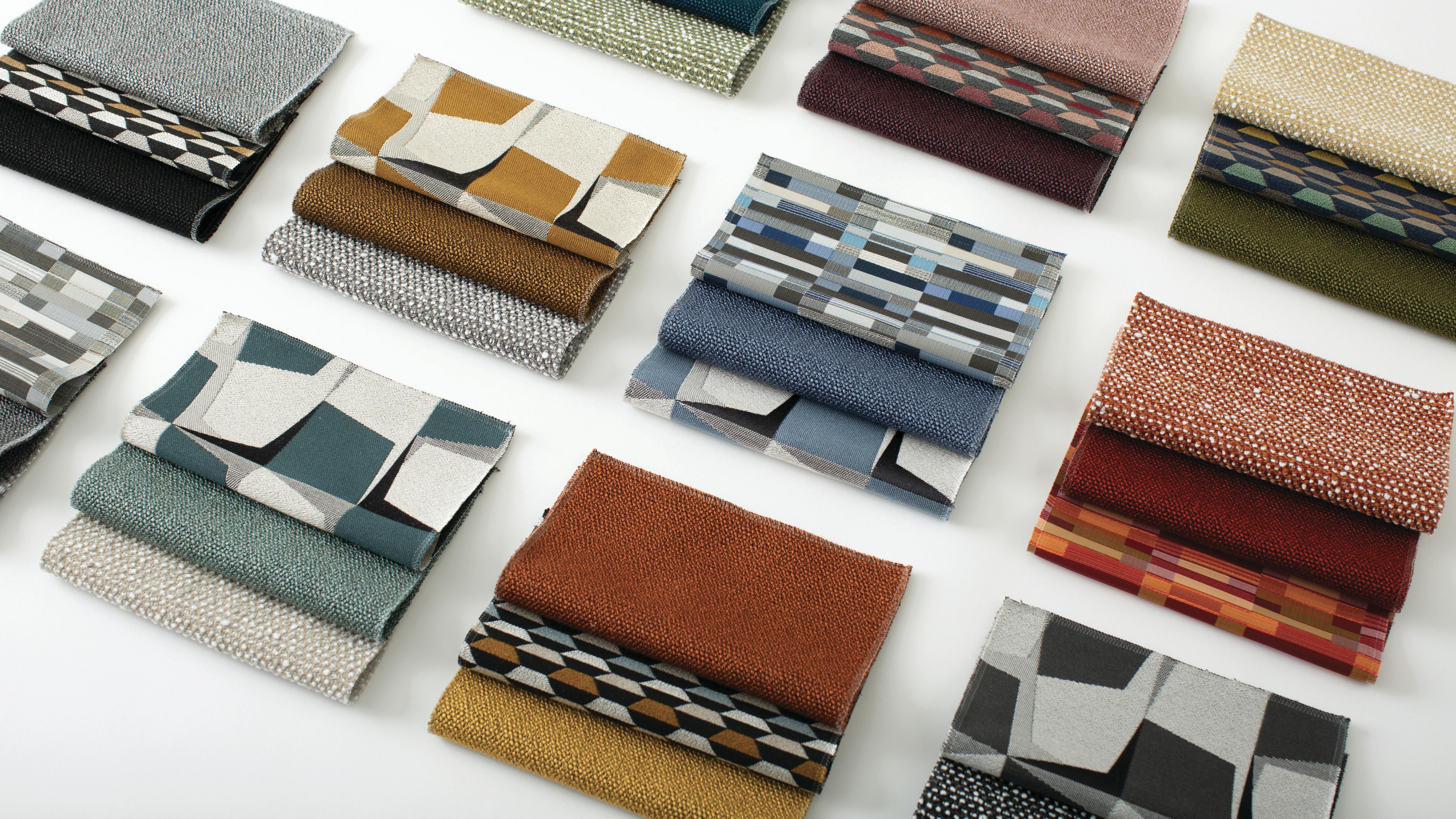 Multiple fabric swatches in various colors and patterns laid out against white backdrop.