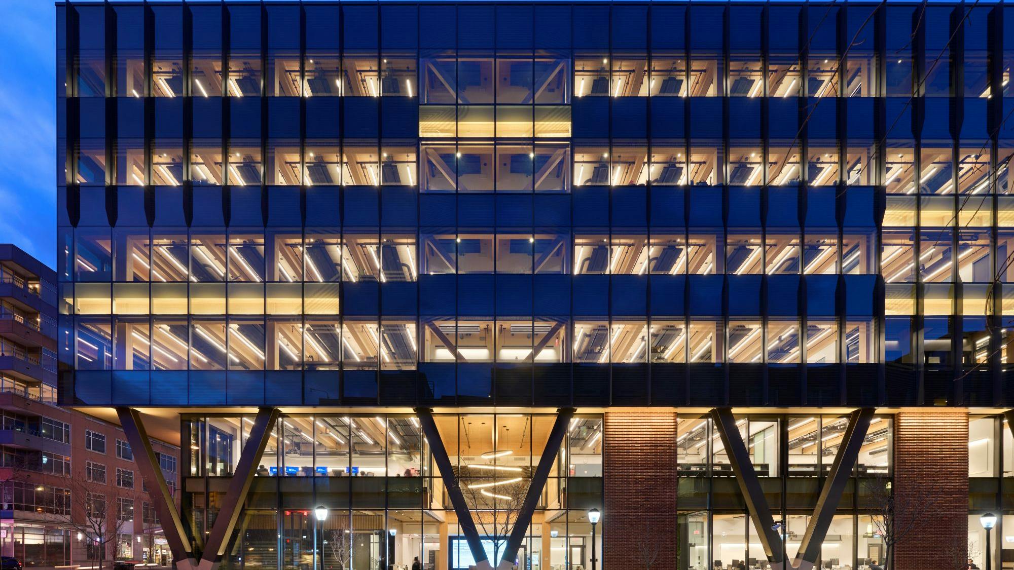Amy Gutmann Hall Exterior lit at night, with expansive glazing and mass timber featuring prominently.